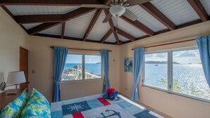 Une chambre avec un lit, un ventilateur de plafond et une vue sur la mer.
