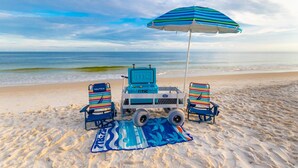 A beach setting with a beach chair, a cooler, and a beach umbrella. - North Hampton: Luxury Gulf Shores Escape (Gulf Shores)