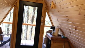Une chambre confortable, aménagée dans un chalet en bois, avec un lit, un petit bureau et une fenêtre donnant sur les arbres.