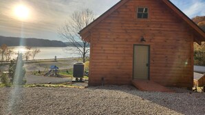 Una cabaña de madera con puerta, una ventana pequeña y un camino de grava.