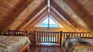 Un dormitorio acogedor en el ático, con vigas de madera, un tragaluz y dos camas.