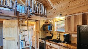 A wooden cabin interior with a loft bedroom, a kitchen with wooden cabinets, a stove, and a refrigerator. - Yellowstone/Hot Tub-Pet friendly-Lakeview -8 Person Lodge (Scio)