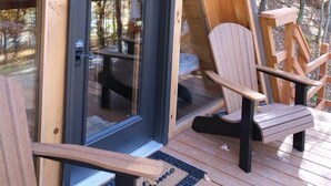 Een houten terras met een deur naar een kamer, omringd door bomen.