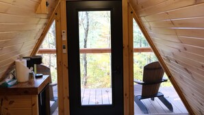 Een gezellig slaapkamer op zolder met een houten schuine dak, een bed, een bureau met een lamp en uitzicht op de omgeving.