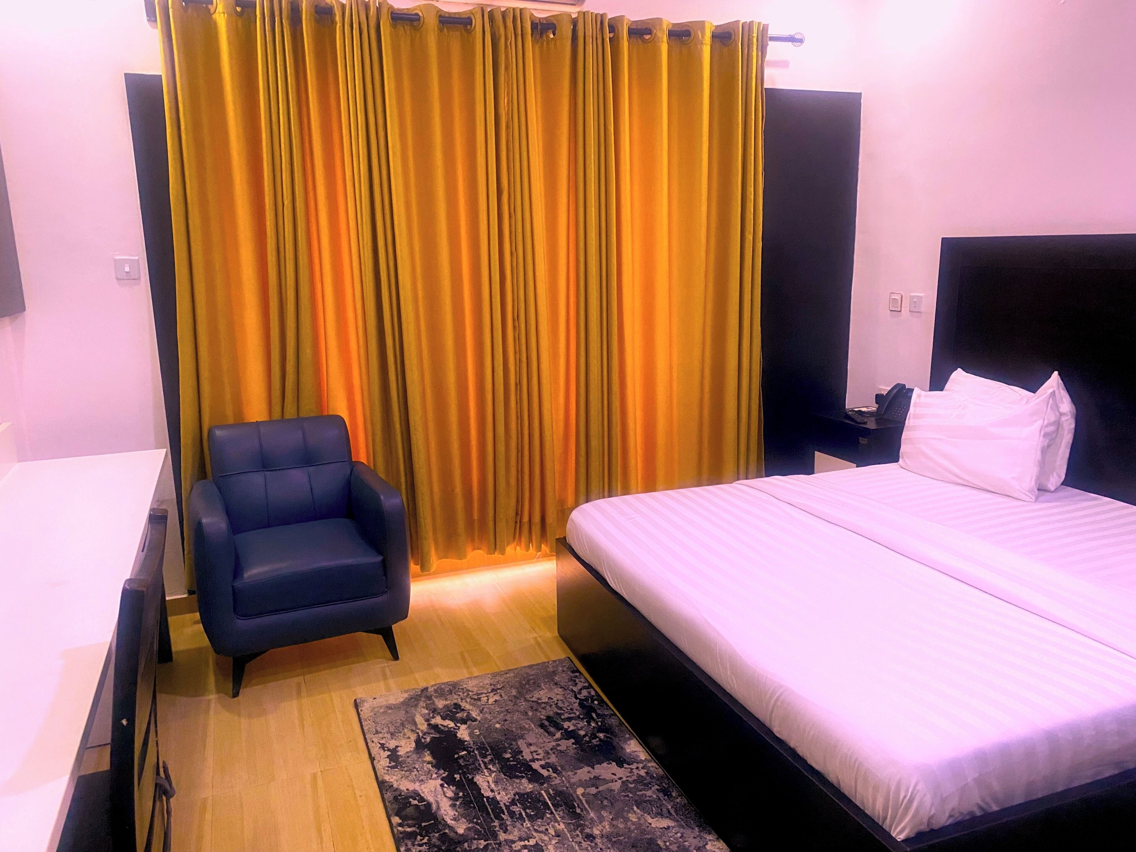 A hotel room with a bed, a chair, a desk, and a curtain.