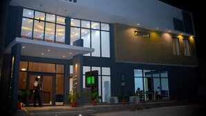 A modern hotel exterior with large windows, a reception area, and potted plants. - Hotel Capitol (Lagos)