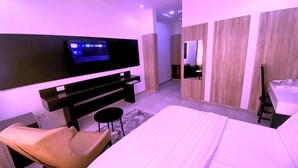 A modern hotel room with a flat-screen TV, a bed, a desk, and a chair. - Hotel Capitol (Lagos)