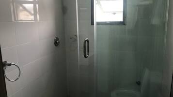 A glass-enclosed shower stall with a toilet, a towel ring, and a door with a handle.
