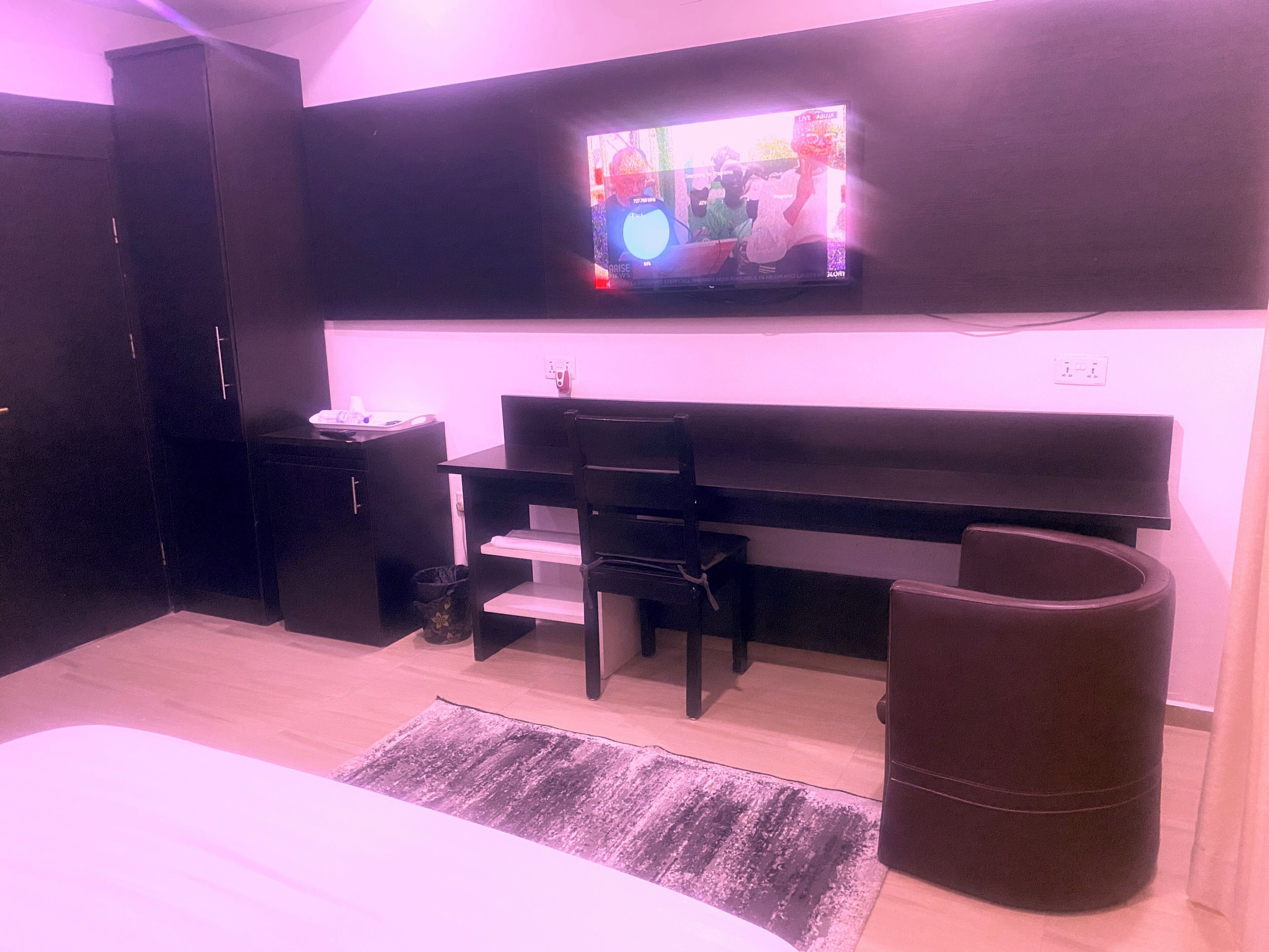 A bedroom with a bed, a desk, a chair, a TV, and a wardrobe.