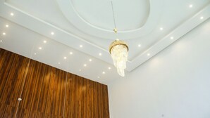A modern interior with a wooden panel wall, recessed ceiling lighting, and a hanging chandelier. - Hotel Capitol (Lagos)