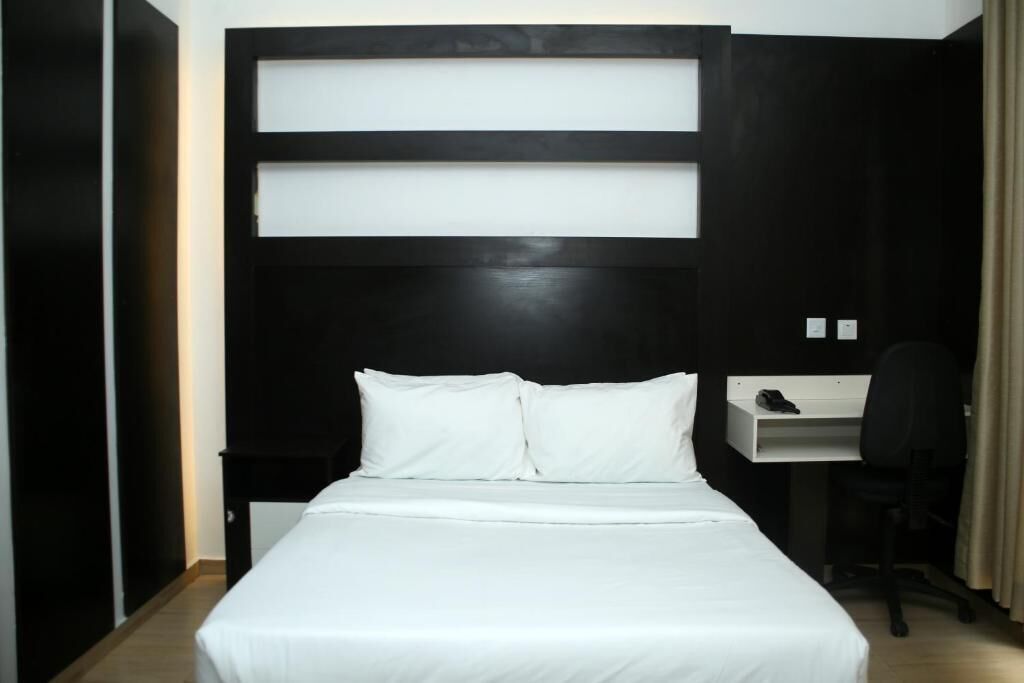 A hotel room with a bed, a desk, and a chair.