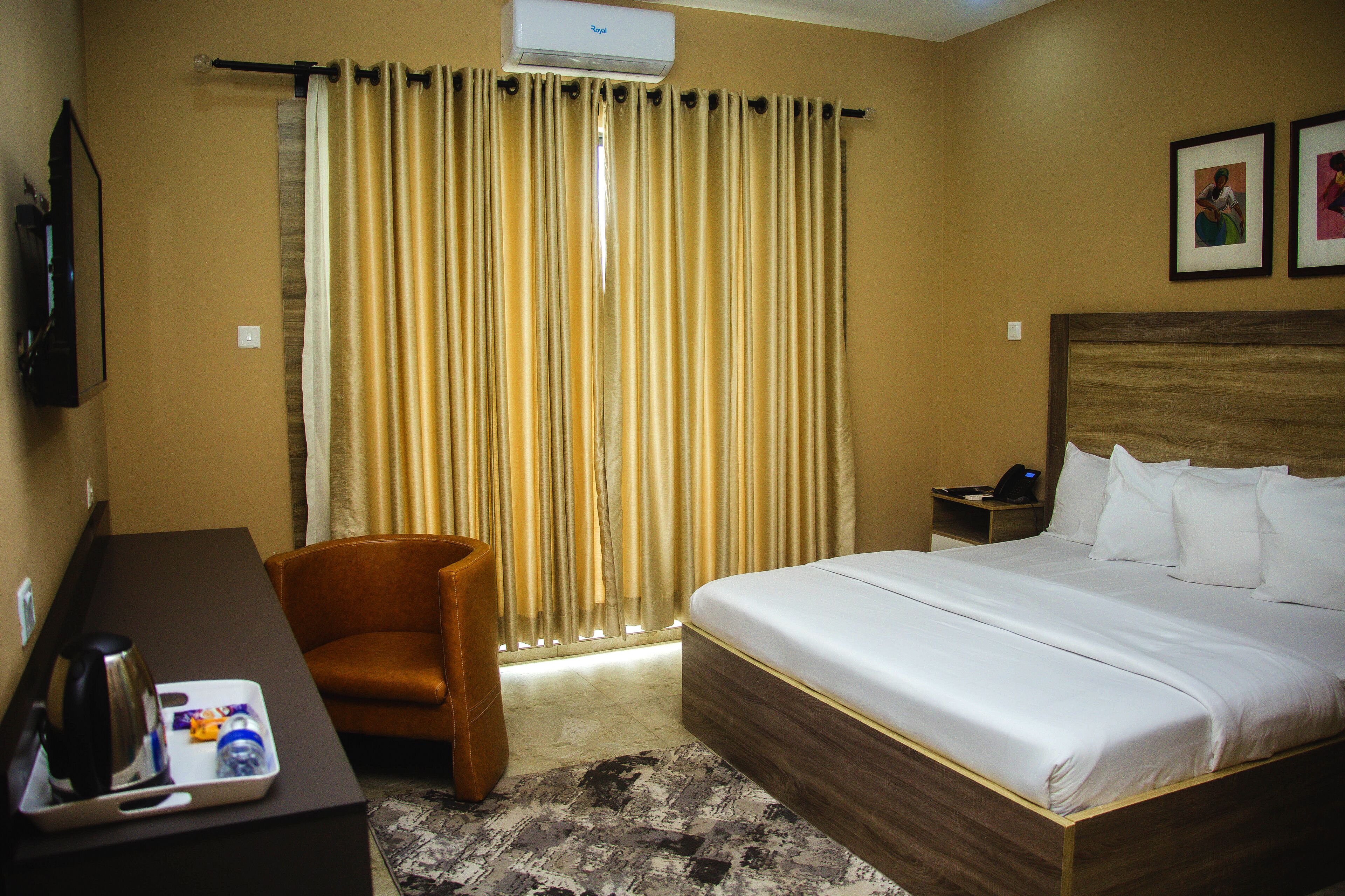 A hotel room with a bed, a desk, a chair, and a window with curtains.