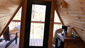 Un dormitorio estilo buhardilla acogedor con techo inclinado de madera, un ventanal grande, una cama, un escritorio y un ventilador de techo.