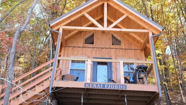 A wooden cabin with a balcony and a name sign reading "KENAI FJORDS". - Kenai Fjord/Lakeview 4-6 Person Midsize Cabin (Franklin Township)