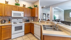 Una cocina moderna con armarios de madera, un microondas blanco, una estufa y un lavavajillas.