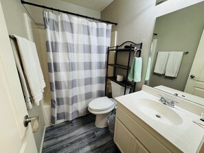 A bathroom with a toilet, a sink, a shower curtain, and a towel rack.