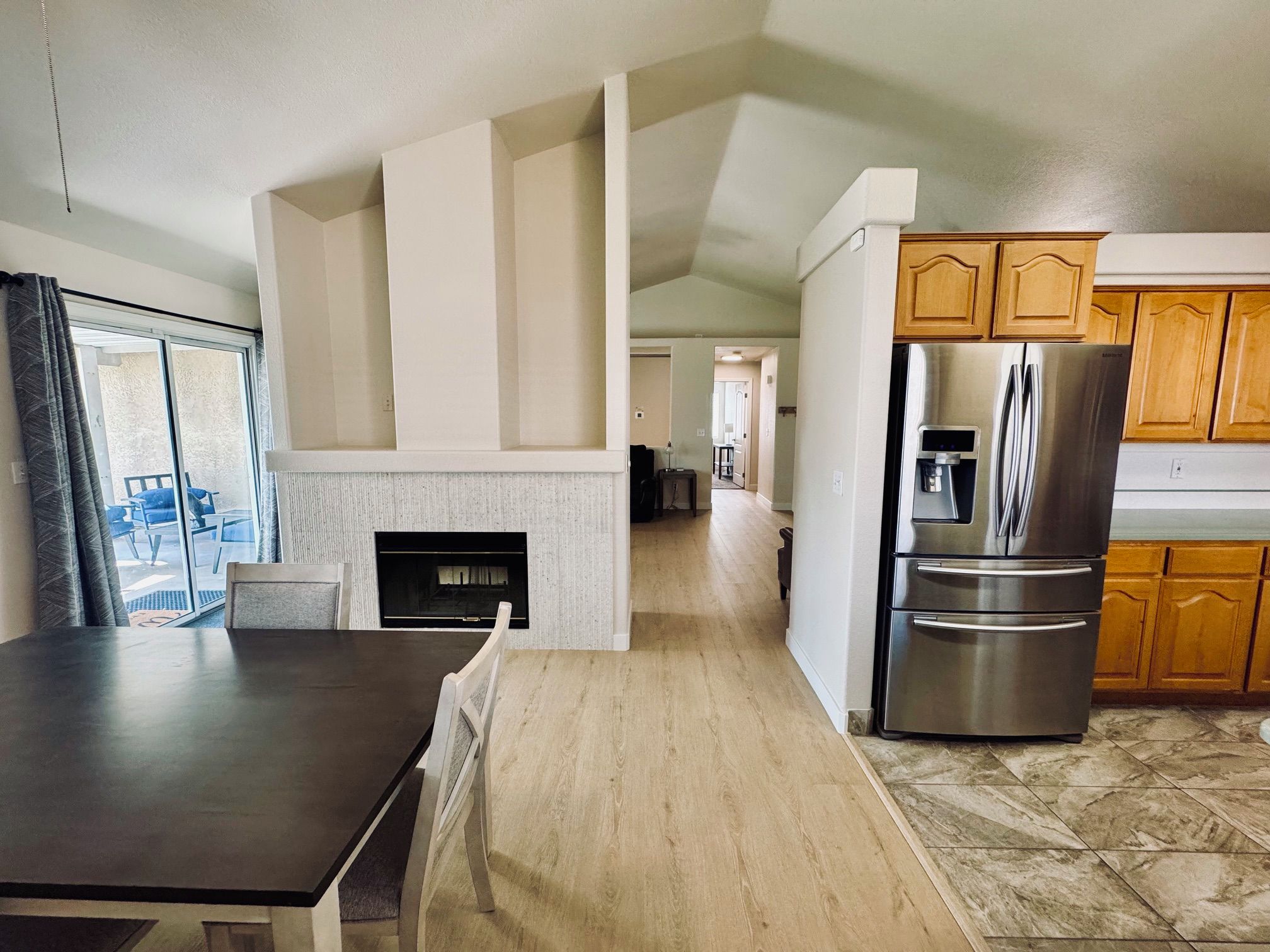 Una cocina moderna con refrigerador empotrado, gabinetes de madera y un comedor con mesa y sillas.