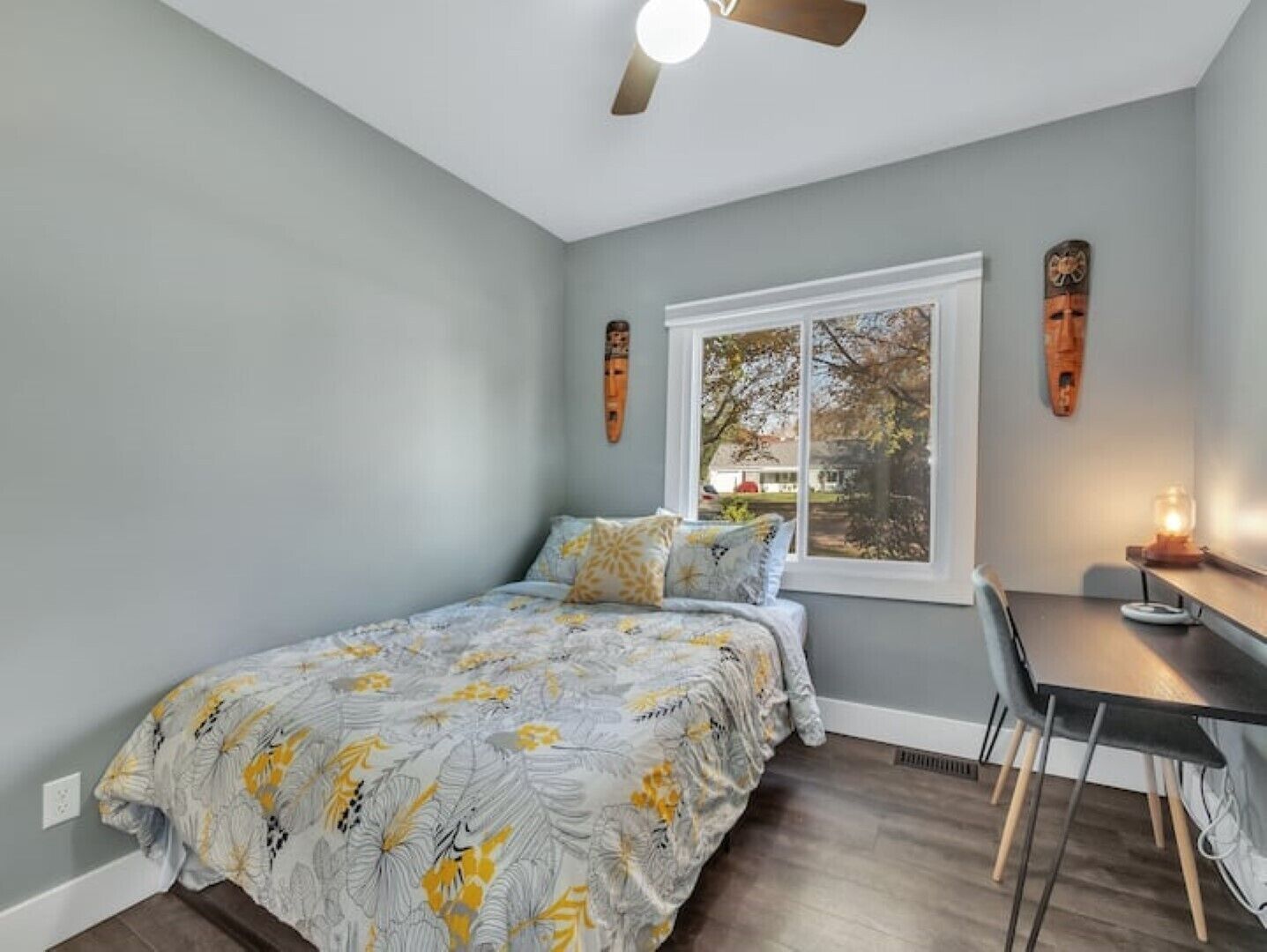 A bedroom with a bed, a desk, and a window.