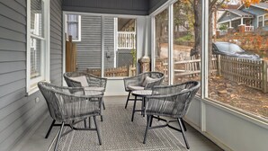 Eine überdachte Terrasse mit Korbmöbeln und Blick auf eine Wohngegend.