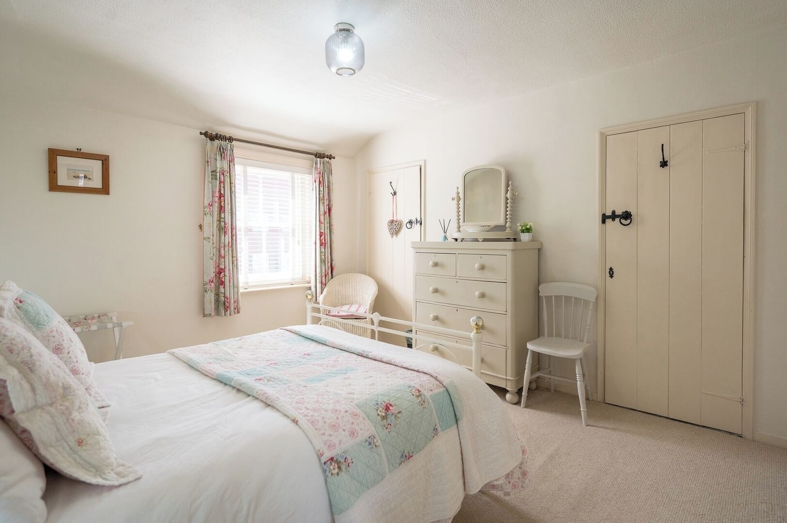 A bedroom with a bed, dresser, chair, and wardrobe.