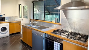 Una cucina moderna con piano cottura in acciaio inossidabile, lavello doppio, lavastoviglie integrata e un'ampia finestra vista esterna.