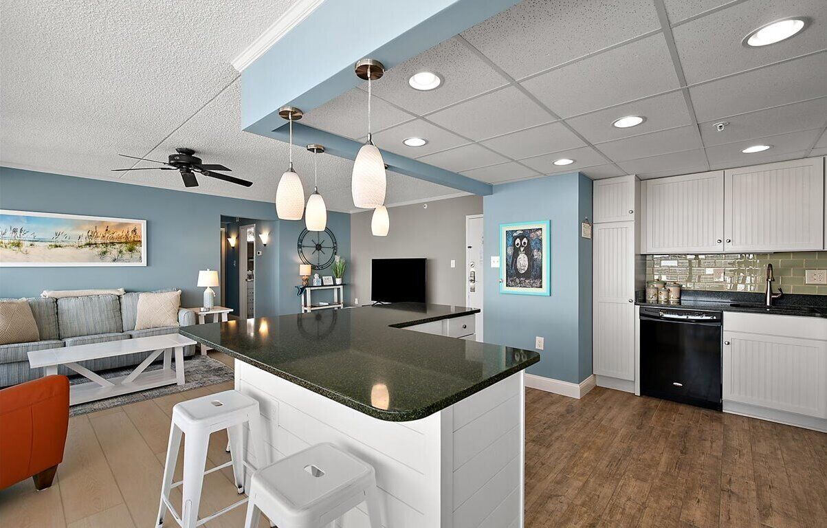 A modern kitchen with a central island, white cabinetry, and pendant lighting.