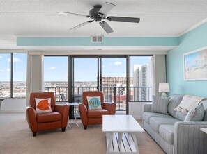 Relax in this stylish living room with a panoramic city view, comfortable seating, and a ceiling fan.