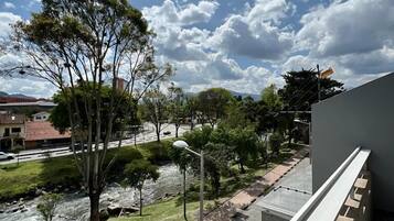 A river flowing through a park with trees and a car parked on the side of the road.