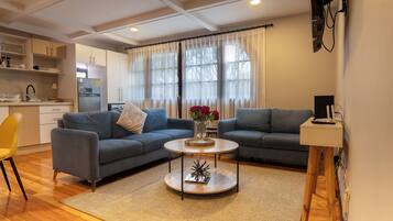 A modern living room with two sofas, a coffee table, and a kitchen in the background.