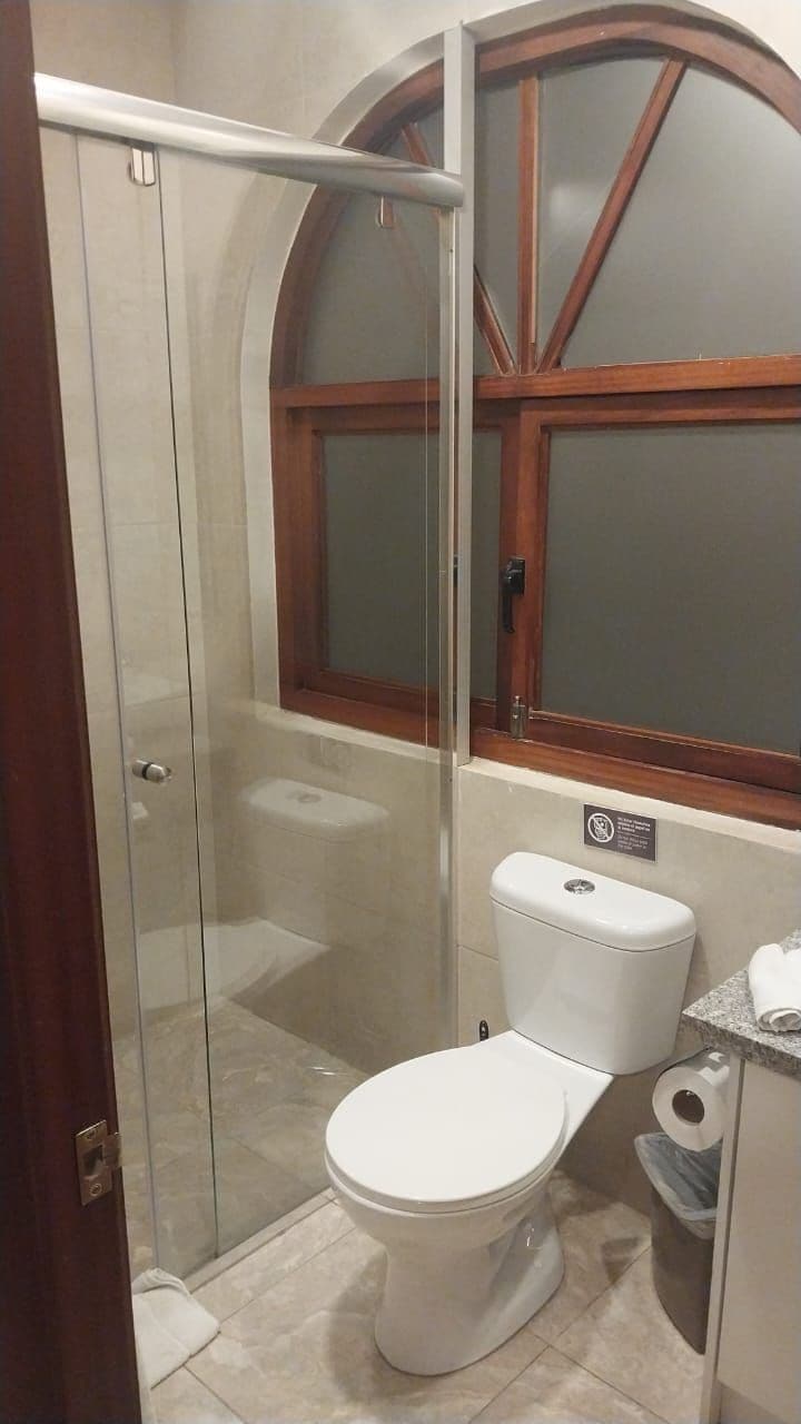 Un baño con ducha de vidrio, inodoro y ventana.