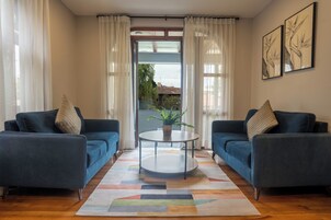Una sala de estar con dos sofás azules, una mesa de centro redonda y una alfombra colorida.