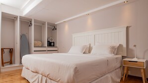 A bedroom with a large bed, a bedside table, a wardrobe, and a hanging rack. - Santa Lucia Suites - Barranco (Cuenca)