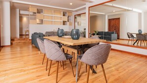 A modern dining area with a wooden table, six chairs, and decorative vases. - Santa Lucia Suites - Barranco (Cuenca)