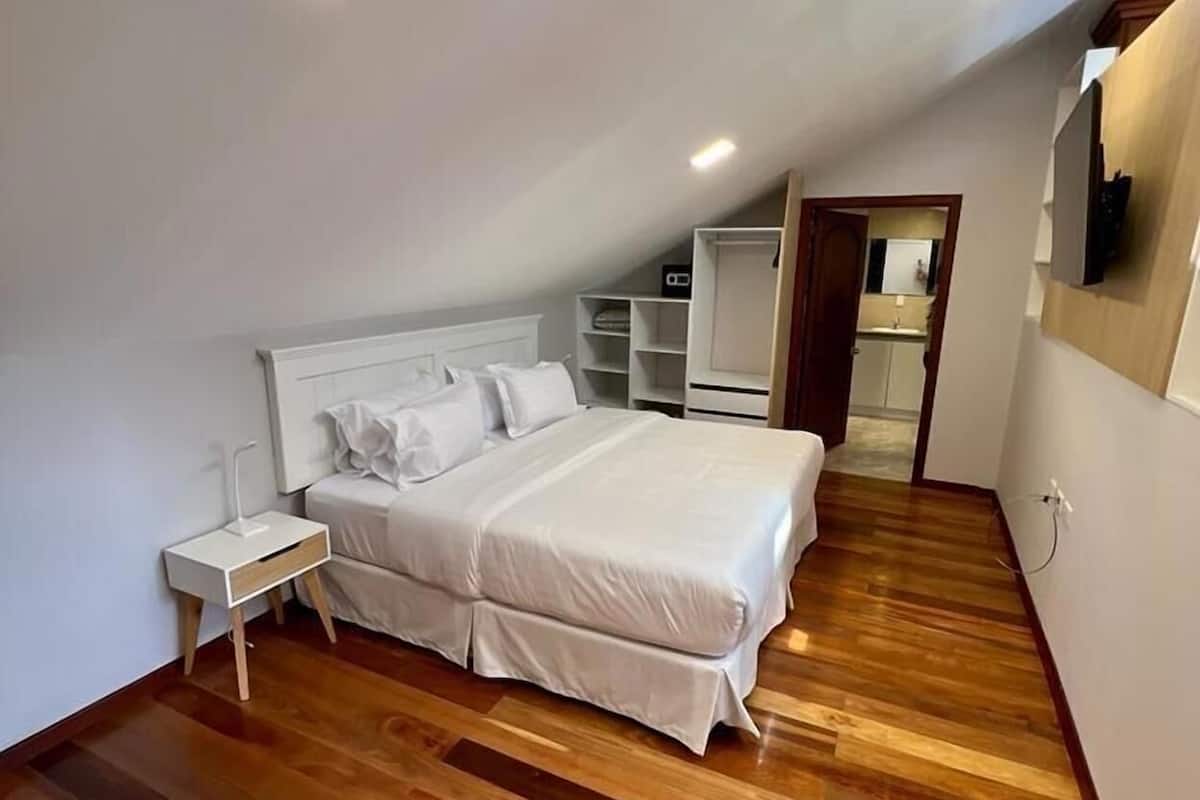 A bedroom with a bed, bedside tables, a wardrobe, and a chair.
