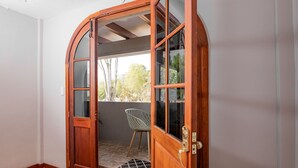 A wooden door with glass panels leading to a balcony with a chair. - Santa Lucia Suites - Barranco (Cuenca)