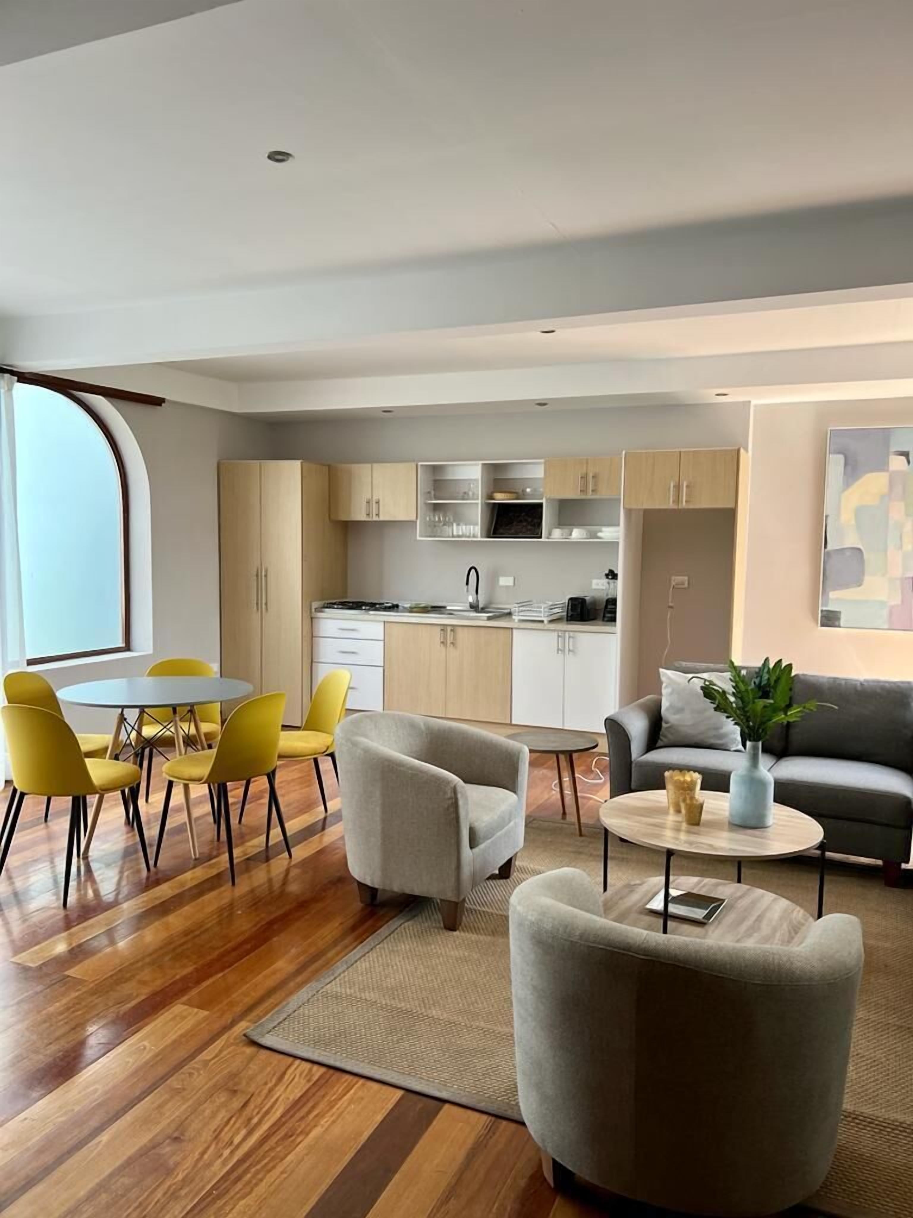 Una sala de estar moderna con comedor, cocina y un sofá gris.