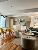 Una sala de estar moderna con comedor, cocina y un sofá gris.