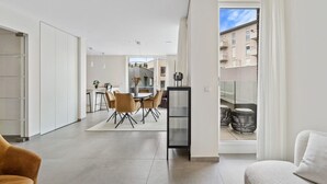 A modern apartment with a dining area, kitchen, and balcony.