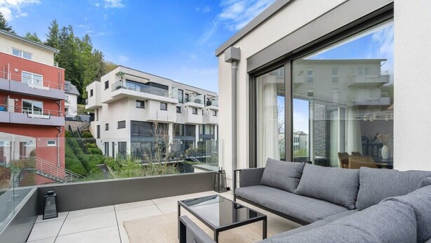 A modern apartment with a balcony, a sofa, and a glass table.