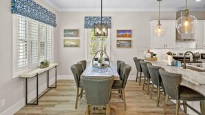 A modern kitchen with a central island, bar stools, pendant lighting, and a window with blinds. - Steps to Ice Plant, in Downtown St Augustine (St. Augustine)