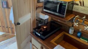 Eine kompakte Küche mit Holzausstattung, einer Mikrowelle, einem Spülbecken und einer kleinen Arbeitsfläche.