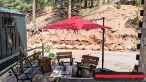 A patio with a red umbrella, wooden benches, and potted plants.