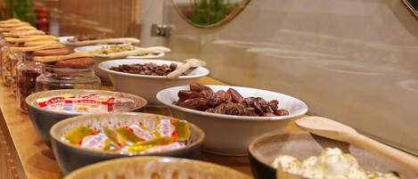 A buffet with various food items including bowls of yogurt, fruits, and other snacks.