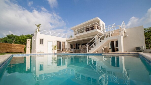 Ein modernes, zweistöckiges Haus mit Schwimmbad, Außenbereich und einer Treppe, die zu einem Balkon führt.