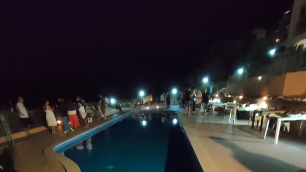A swimming pool with a curved edge, surrounded by a tiled deck area.