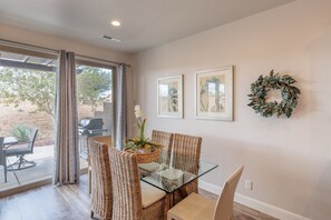 A dining area with wicker chairs, a glass table, and a wreath on the wall. - Contemporary 4BR w/ 2 Kings - Near 18th Fairway (St. George)