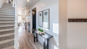 Un intérieur moderne avec un escalier, un couloir menant à la cuisine et un coin repas.