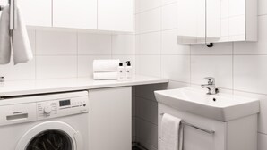 Un baño moderno con una lavadora blanca, un lavamanos y un espejo encima.