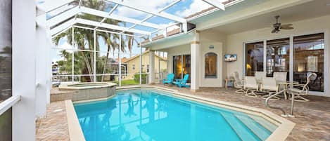 A pool area with a glass ceiling, outdoor seating, and a view of palm trees.