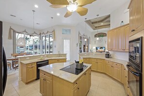 Eine geräumige Küche mit einer großen Kochinsel, Holzschränken und einem modernen Deckenventilator.